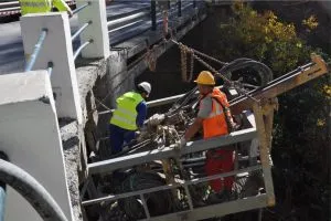 Operarios reparando el tablero de un puente desde una plataforma